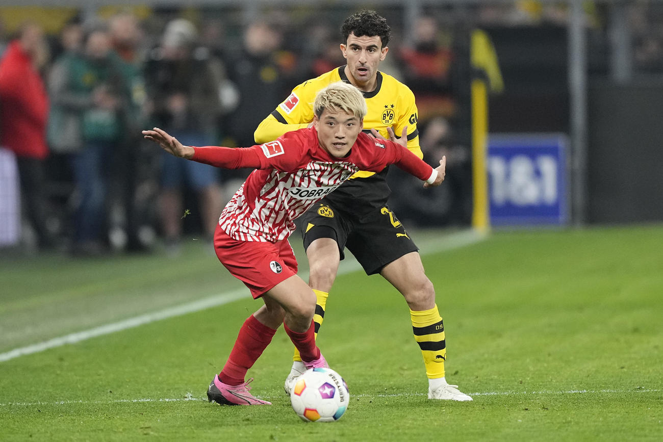 ドルトムント戦、相手選手と競り合うフライブルク堂安律（左）（AP）