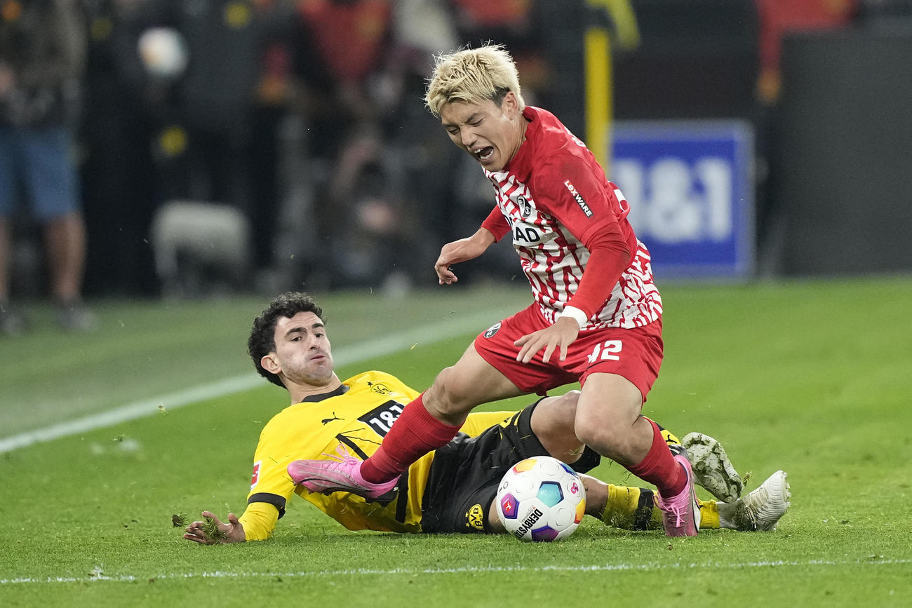 ドルトムント戦、タックルを受けて顔をゆがめるフライブルク堂安律（右）（AP）