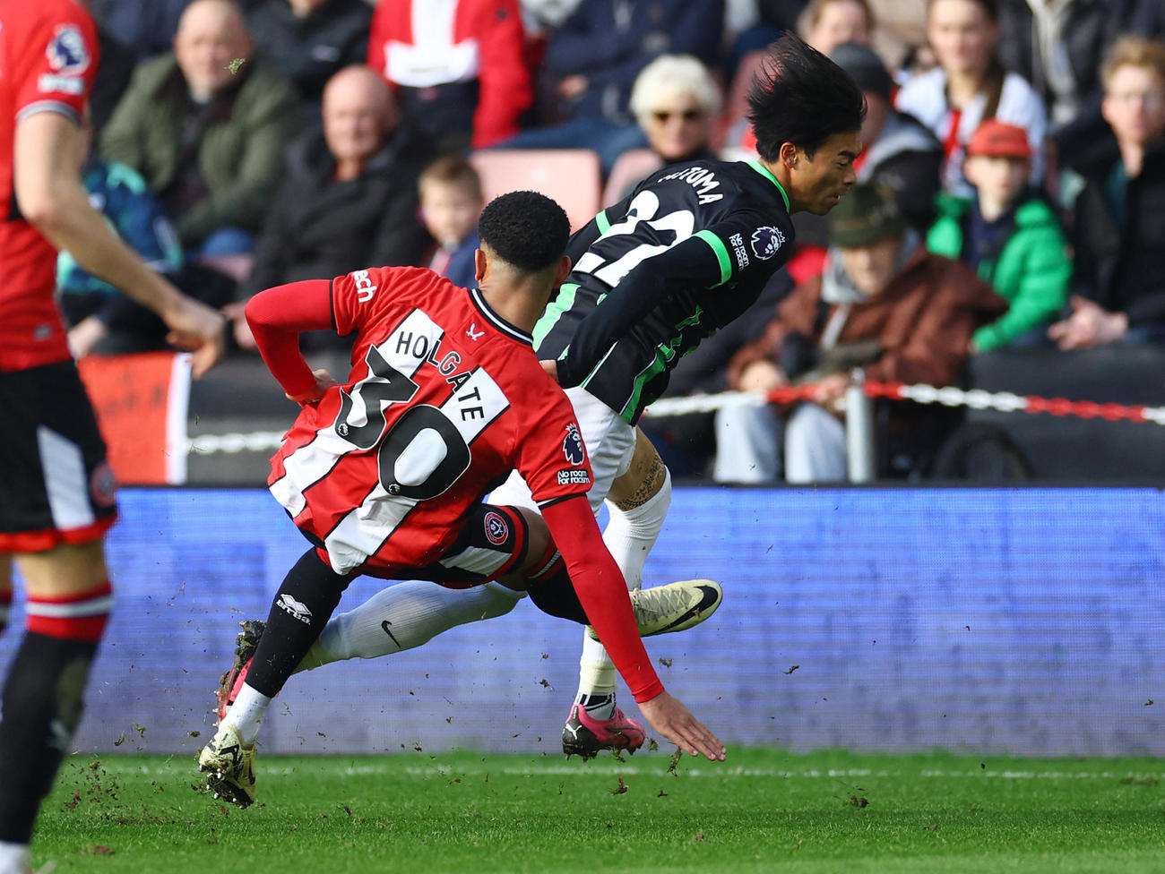 左膝の辺りにタックルを受ける三笘（ロイター）