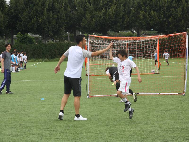 サッカー教室で参加者の子どもとハイタッチする吉田麻也