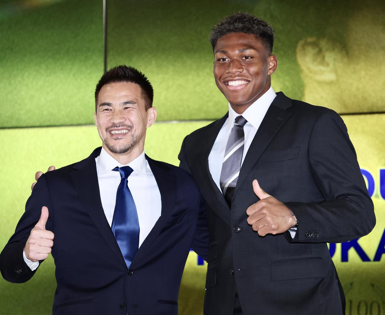 引退会見で、チームメートのシントトロイデンGK鈴木（右）と笑顔で肩を組む岡崎（撮影・河田真司）