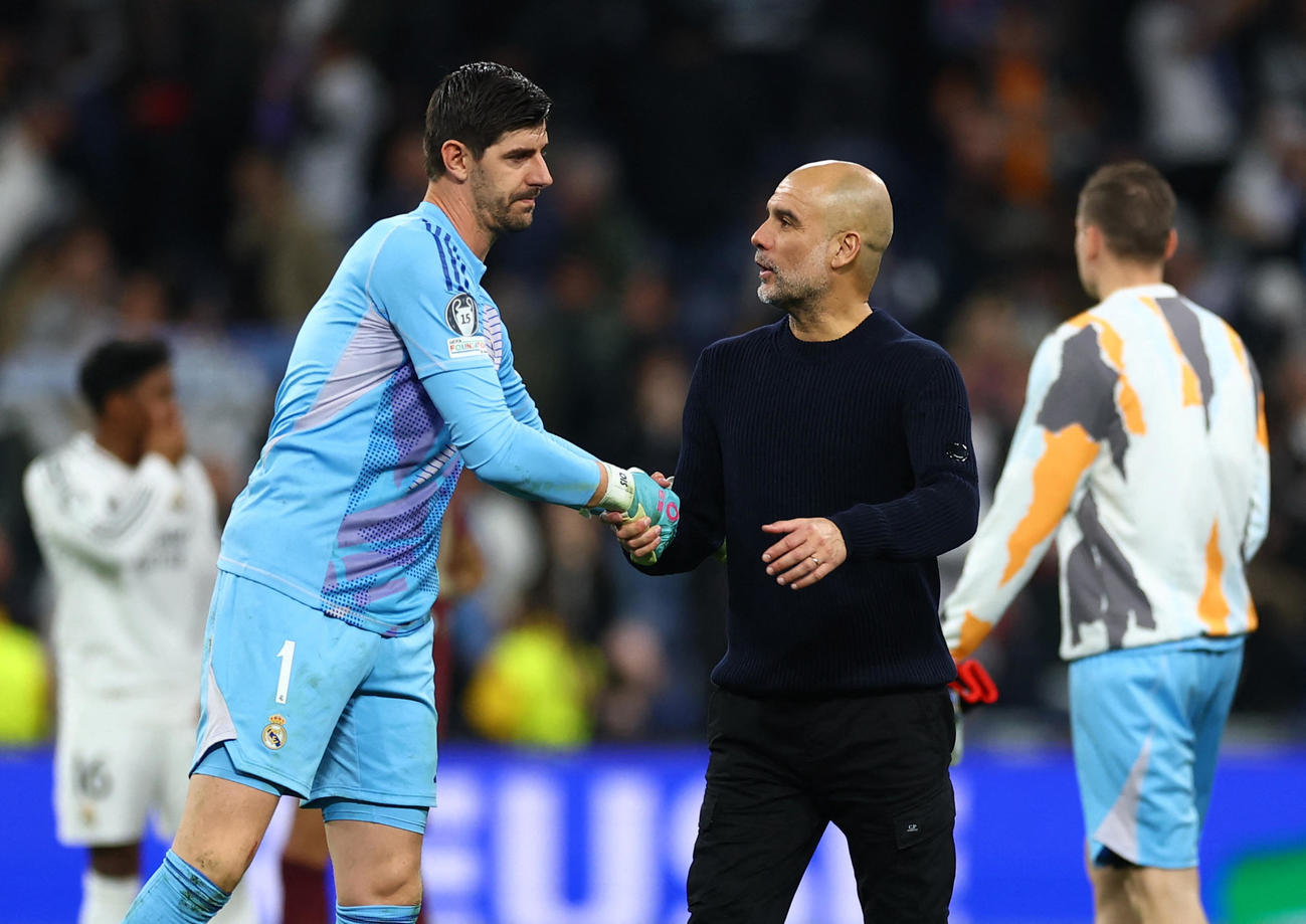 試合後、レアル・マドリードのGKティボー・クルトワ（左）と握手するマンチェスター・シティーのグアルディオラ監督（２０２５年２月１９日、ロイター）