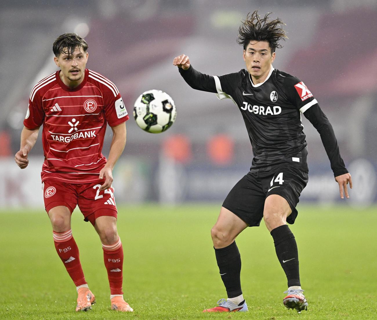 デュッセルドルフ戦で競り合うフライブルクの鈴木（右）（共同）