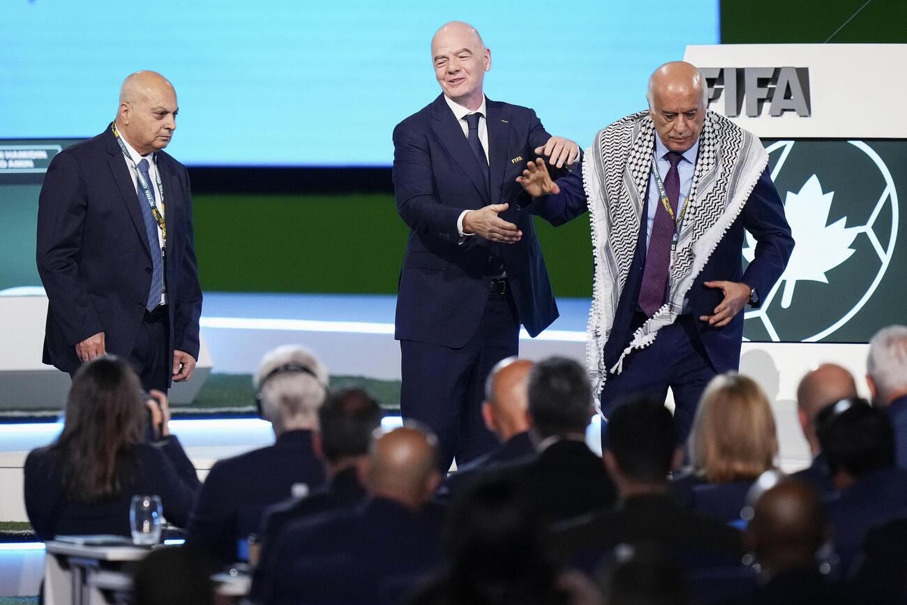 FIFAの総会で壇上から立ち去るパレスチナ協会のラジューブ会長（右）。左はイスラエルの代表、中央はFIFAのインファンティノ会長（AP＝共同）