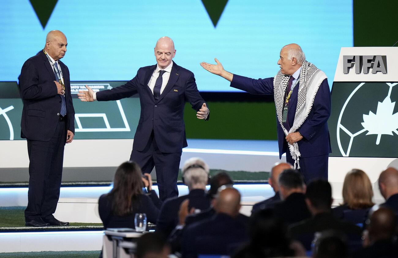 FIFAの総会でイスラエルの代表（左）と並び立つことを拒否するパレスチナ協会のラジューブ会長（右）。中央はFIFAのインファンティノ会長（AP＝共同）