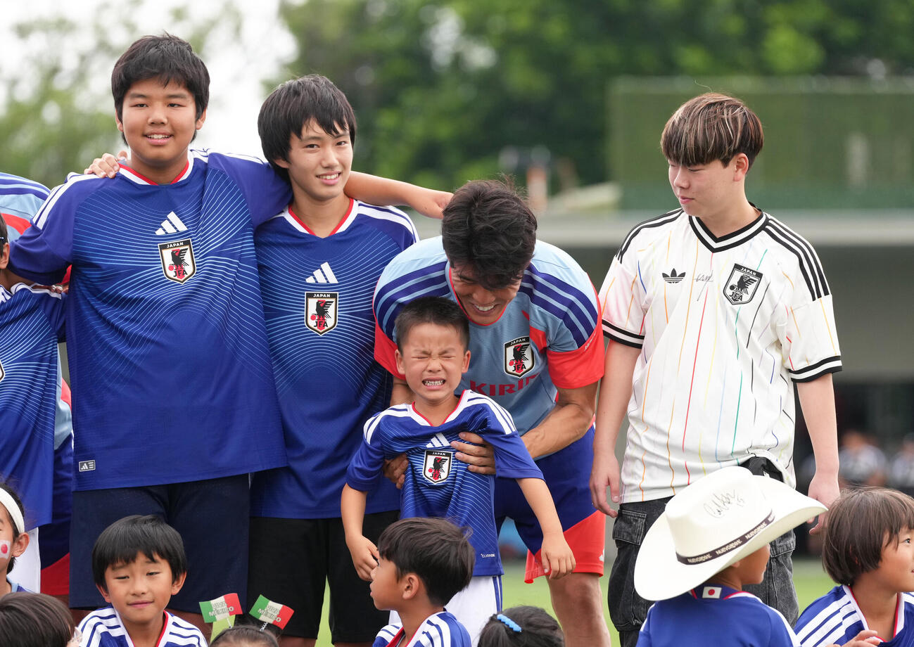 サッカー日本代表W杯北中米大会事前合宿　練習前、記念撮影の際、泣き出してしまった子どもに戸惑いの表情を見せる冨安健洋（撮影・足立雅史）