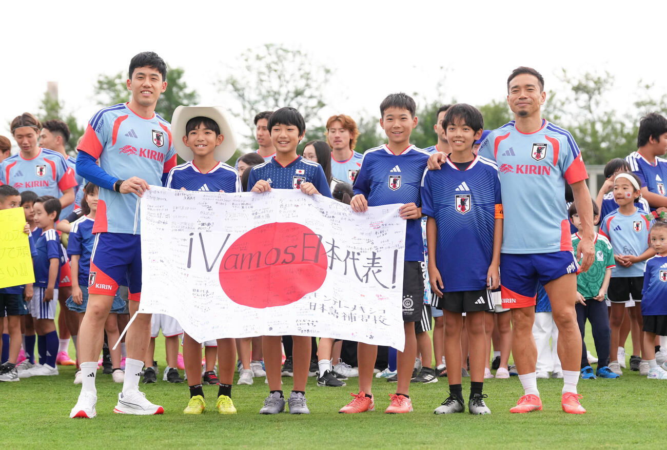 サッカー日本代表W杯北中米大会事前合宿　練習前、現地の子どもたちから応援メッセージの入った日の丸を受け取る遠藤航（左端）と長友佑都（右端）（撮影・足立雅史）