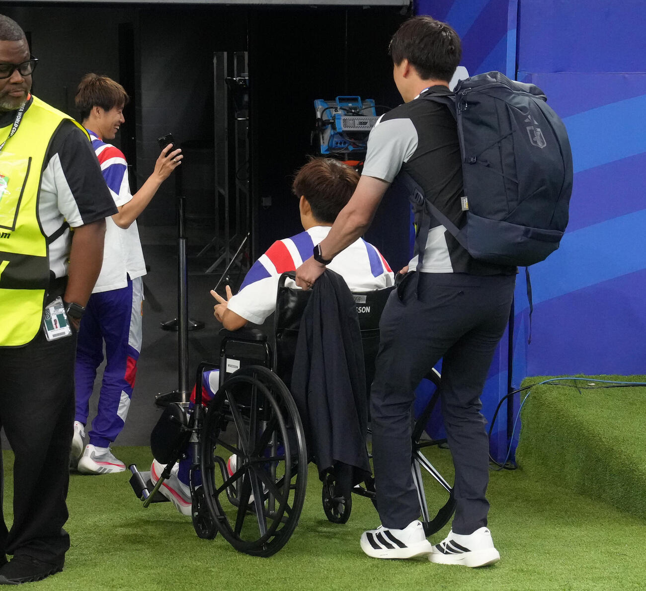 日本対オランダ　試合後、車いすでスタジアムを後にする久保建英（中央右）のピースサイン姿を撮影する鎌田大地（撮影・足立雅史）