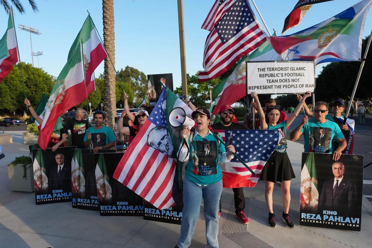 イラン政権に反対する抗議者たちがプラカードを掲げ、メガホンを使って訴えかけている（ロイター）