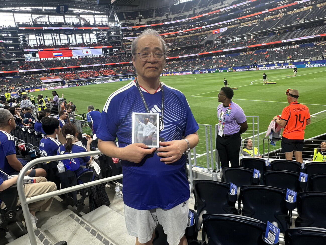 14日、日本のW杯初戦、オランダ戦のスタンドで釜本邦茂さんの遺影を持って観戦する坂井信幸さん（清仁会シミズ病院坂井信幸院長提供）