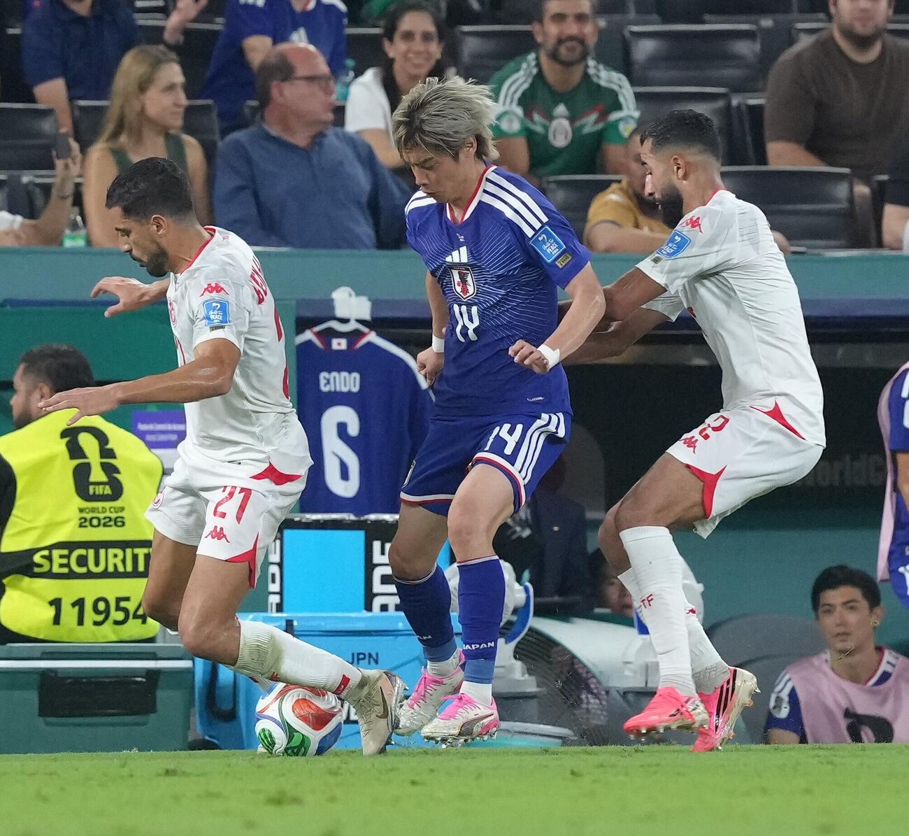 日本対チュニジア　後半、チュニジア代表選手と激しく競り合う伊東純也（中央）（撮影・足立雅史）