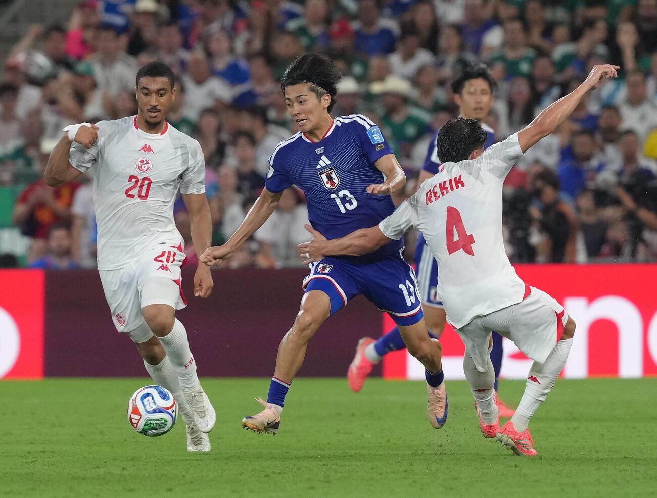 日本対チュニジア　後半、チュニジア代表選手と激しく競り合う中村敬斗（中央）（撮影・足立雅史）
