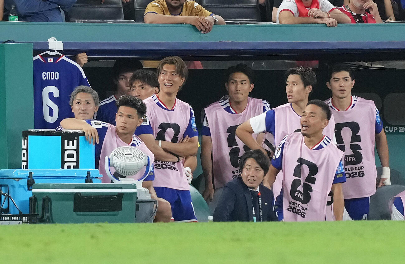 日本対チュニジア　後半、ベンチから戦況を見つめる長友佑都（手前右端）ら。左端には遠藤航のユニホームが掲げられている（撮影・足立雅史）