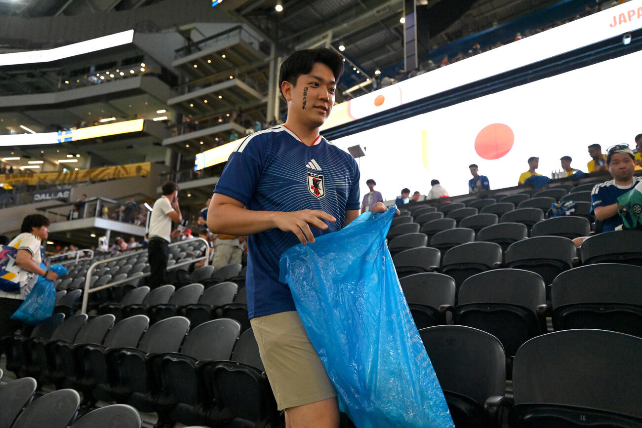 スタンドでごみ拾いをする日本のサポーター（AP）