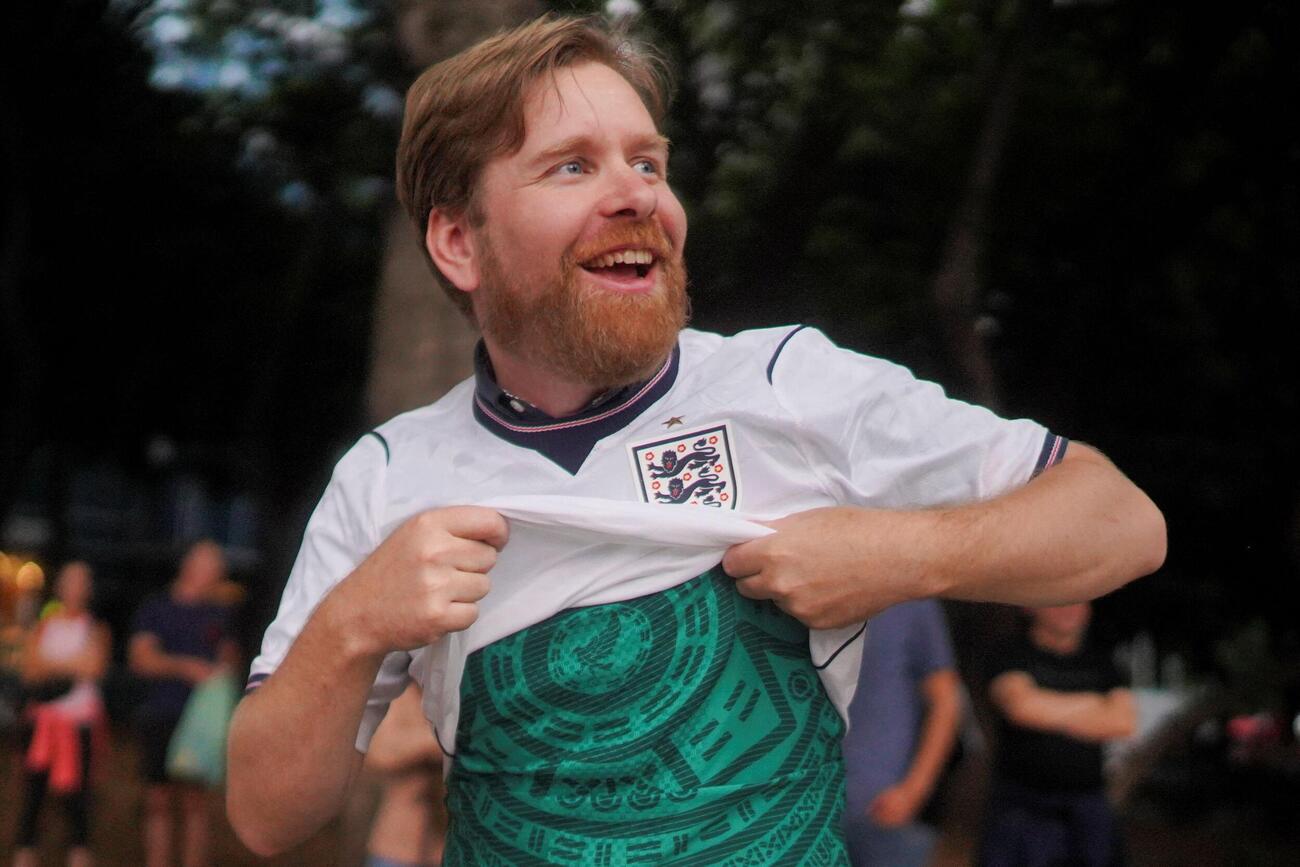 2026年7月4日、メキシコのメキシコシティにて、サッカーのFIFAワールドカップ・決勝トーナメント1回戦、メキシコ対イングランド戦を前に、イングランド代表のユニホームの下に着ているメキシコ代表のユニホームを見せるイングランド代表サポーターのアラン・ルイスさん（ロイター）