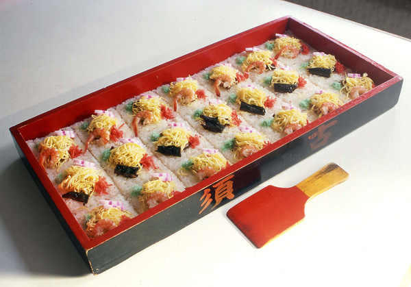 浅い木箱にすし飯を敷いて軽く押さえ、食べやすい大きさに筋目をつける。その筋目に従ってすし飯の上に具を飾り付ける。具材は特に決まっていないが、ニンジン、シイタケ、カンピョウ、カマボコ、この地の特産ムツゴロウのつくだ煮など。須古地区限定。