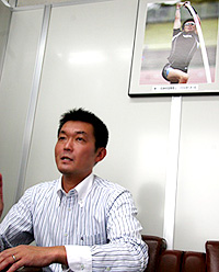 沢野の写真の前でインタビューに答える米倉照恭（２００７年７月１９日）