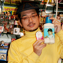 コレクションの前でお気に入りの水筒を手に笑顔のやく氏