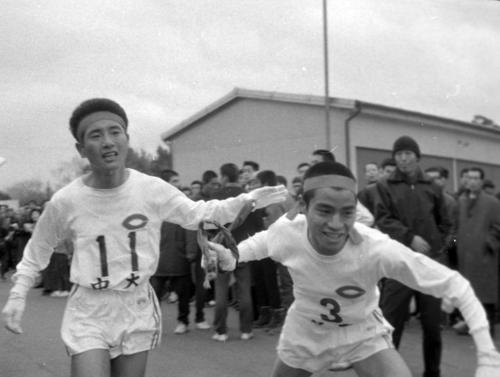 第４０回大会　３区戸塚中継所　中大の２区、碓井哲雄（左）から２位でタスキをもらう師岡溢哺（右）（１９６４年１月２日）