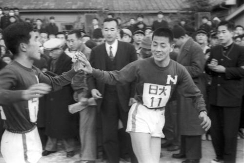 第34回大会　復路8区平塚中継所　7区松川行毎（左＝4年）から8区中村次義（右＝2年）にタスキリレーするトップ日大（1958年1月3日）