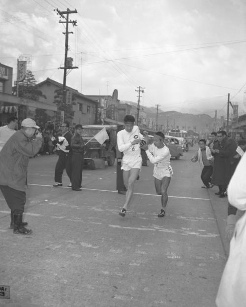 第35回大会　復路7区小田原中継所　トップ中大は6区作田誠一（左＝3年）から7区山崎務（右＝1年）にタスキリレー、2位日大との差は6分23秒に広がる（1959年1月3日）