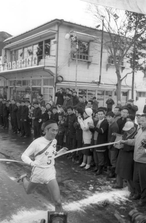 第38回大会　往路5区郵便局前　4連覇を目指す中大は、1区からトップを譲ることなく2位法大に3分45秒差をつけ往路アンカー中島輝雄（2年）がゴール（1962年1月2日）
