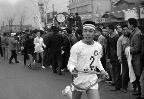 第40回大会　往路2区鶴見中継所　トップでタスキを受けた国士舘大・木原了（2年）、後方は1区区間新の大川賢明（1年）（1964年1月2日）