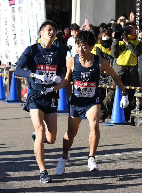 小田原中継所に1位で到着し、7区小笹（右）にたすきを渡す東洋大1区今西（撮影・鈴木みどり）