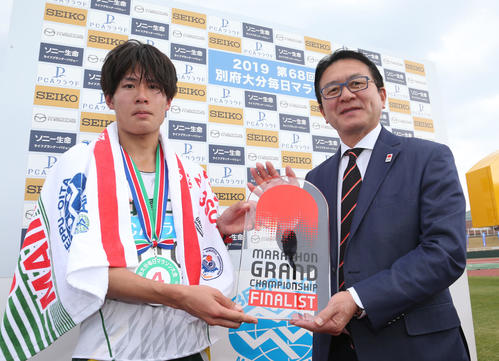 総合4位、日本人1位でゴールした二岡康平はマラソン・グランドチャンピオンシップの出場権を獲得。瀬古利彦氏(右)からチケットを受ける(撮影・梅根麻紀)