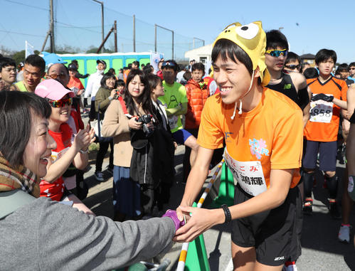 かぶり物でスタート地点に登場し、観衆と握手する川内優輝の弟鴻輝さん（撮影・林敏行）