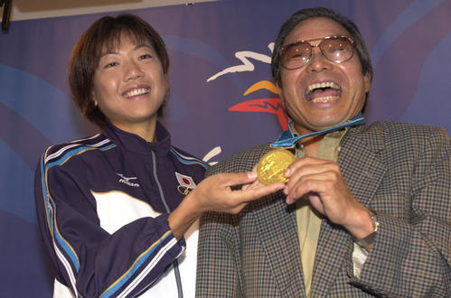 00年9月、シドニー五輪女子マラソン金メダル獲得から一夜明け、高橋（左）からメダルを掛けられ笑顔の小出監督