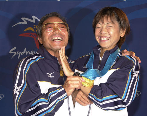 00年9月、シドニー五輪女子マラソンの表彰式後、会見した高橋（右）にヒゲを剃ったアゴをなでられ笑顔の小出監督