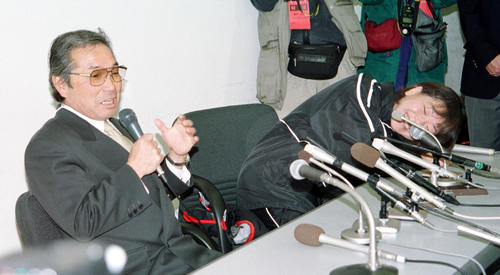 2001年2月4日、丸亀ハーフマラソンの会見の席上、小出義雄監督（左）から「昨日も一昨日も夜になるとメソメソ泣いていたんだ」と裏話を暴露されドテとテーブルに倒れ込む高橋尚子