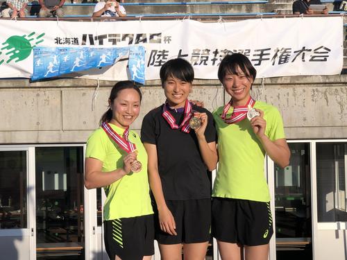 女子100メートルで優勝して表彰台で笑顔の御家瀬（中央）右は2位の島田、左は3位の北風（撮影・上野耕太郎）