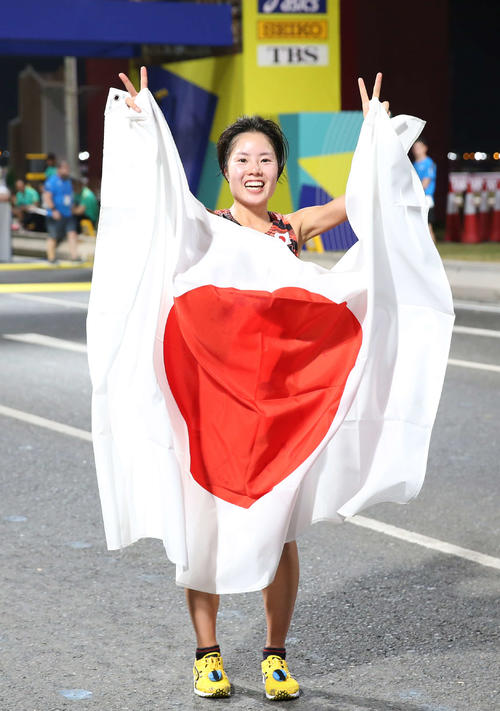 女子マラソン、7位でゴールし日の丸を手にピースサインの谷本（撮影・河野匠）