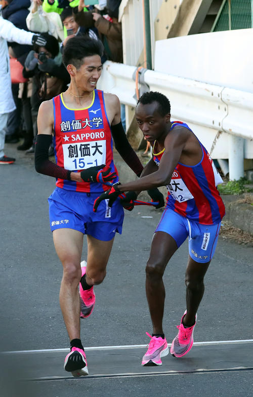 鶴見中継所で創価大2区ムイル（右）にたすきを渡す創価大1区米満（撮影・大野祥一）