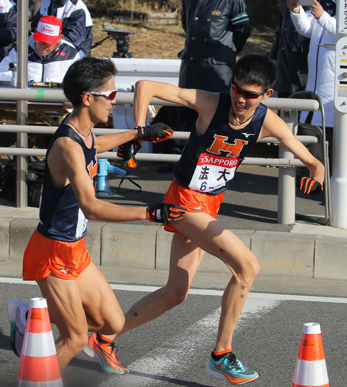 平塚中継所で法大8区中園（右）にたすきをつなぐ7区松沢（撮影・河田真司）