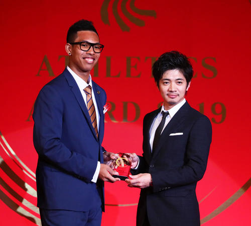 日本陸連の表彰式で、サニブラウン（左）はプレゼンターの和田正人から盾を受け取る（撮影・足立雅史）