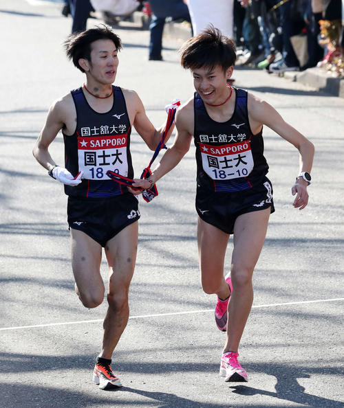 9区国士舘大・福田（左）からたすきリレーする10区孝田（撮影・鈴木正人）