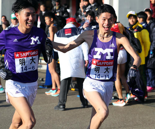 小田原中継所で、明大6区前田（左）の肩を叩く7区阿部（撮影・大野祥一）