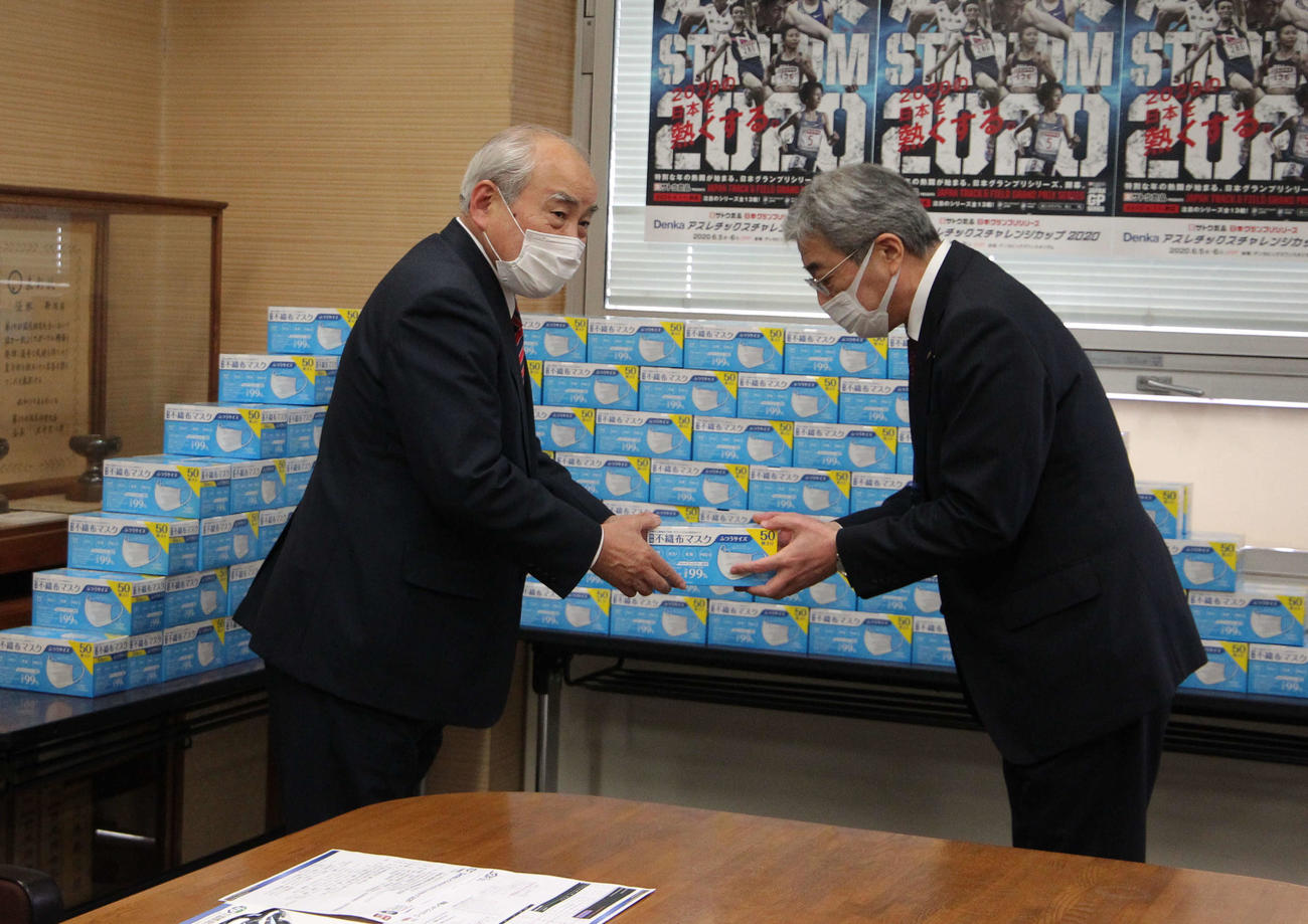 新潟陸協・大橋会長（左）が稲荷教育長にマスク50枚入りの箱を手渡し