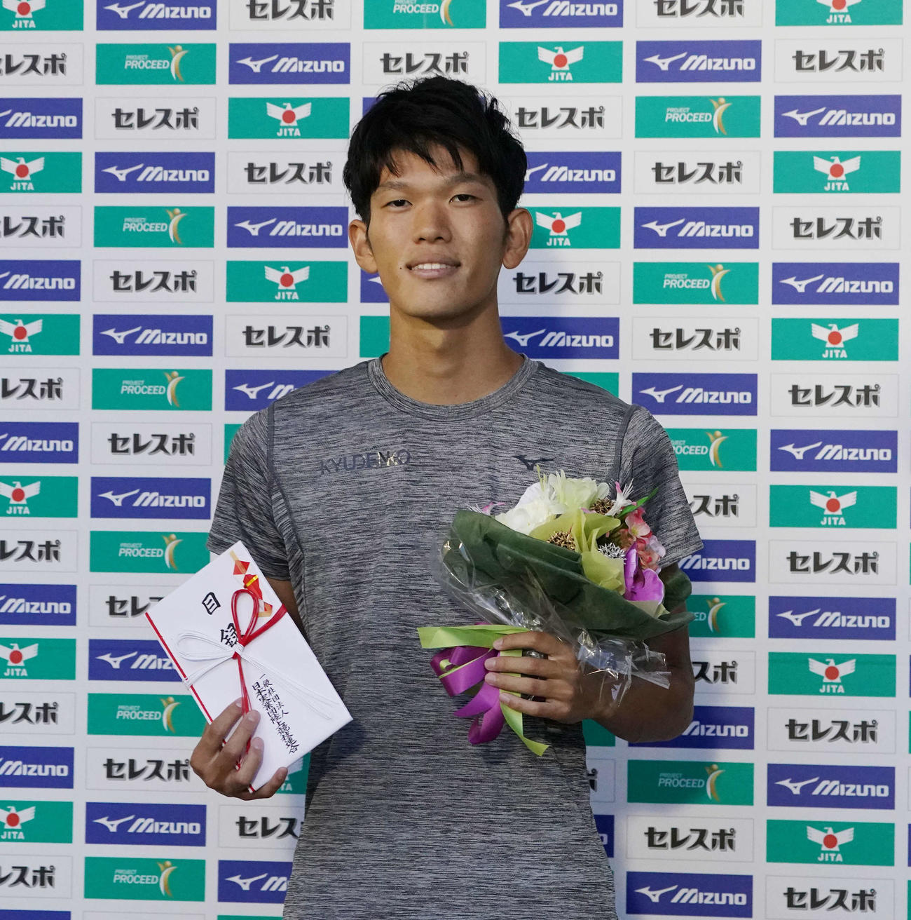 男子走り高跳びで優勝し、花束を手に笑顔の真野（撮影・鈴木みどり）
