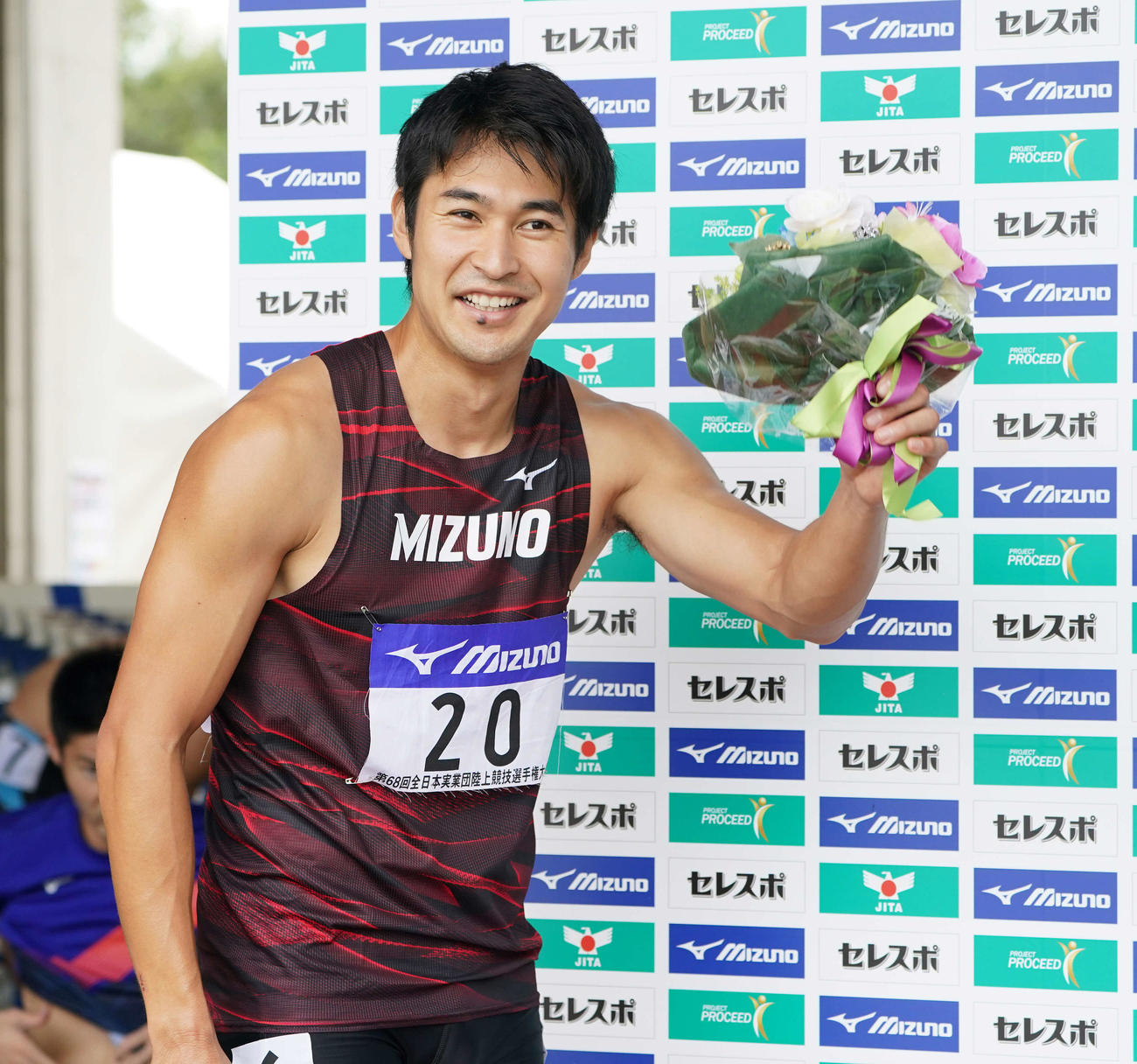 男子200メートルで優勝し花束を手に笑顔の飯塚（撮影・鈴木みどり）