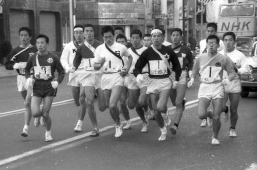 往路1区　午前8時、銀座の読売新聞社横を一斉スタートした15校は一団となって外堀通りを行く。左から4人目は日大・青葉昌幸（4年、のち大東大監督として箱根4連覇）＝1966年1月2日