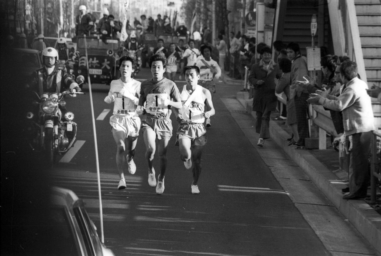 往路1区　蒲田付近でトップ争いをする左から亜大・小林稔（2年、区間3位）、東京農大・岩瀬哲治（3年、区間2位）、日体大・和田誠一（4年、区間1位）＝1976年1月2日