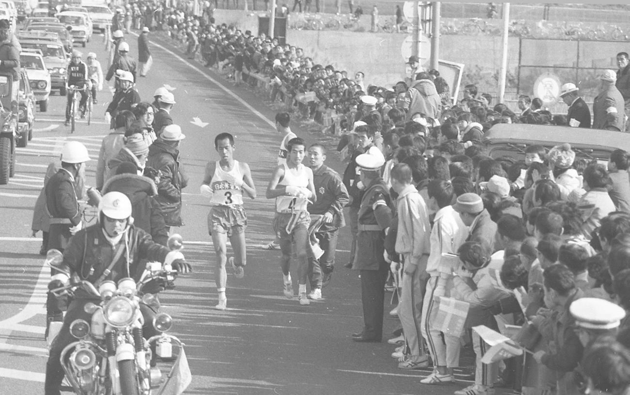 往路4区平塚中継所　2位に1分近くの差をつけタスキリレーする日体大3区中村孝生（左＝1年、区間1位）と4区照井典勝（右＝2年、区間3位）＝1977年1月2日