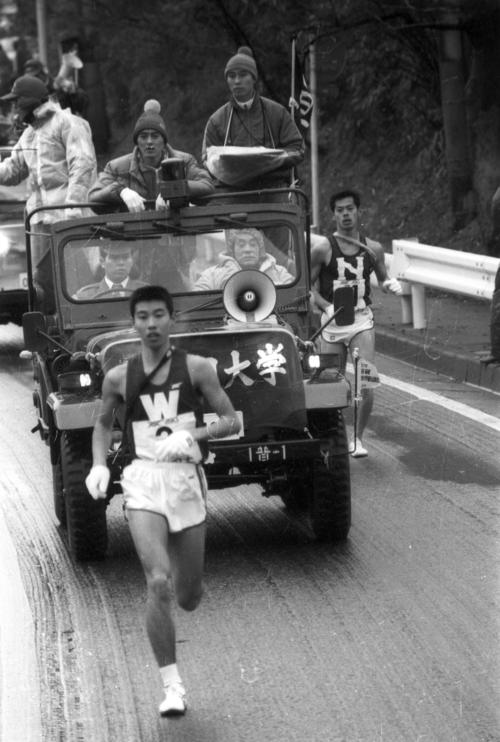 往路3区　7位でタスキを受けた早大・坂口泰（1年、区間8位）を伴走車の上から懸命に激励する先輩の瀬古利彦（中央＝24歳、ヱスビー食品）、右後方は8位の日大・河出千里（3年、区間13位）＝1981年1月2日