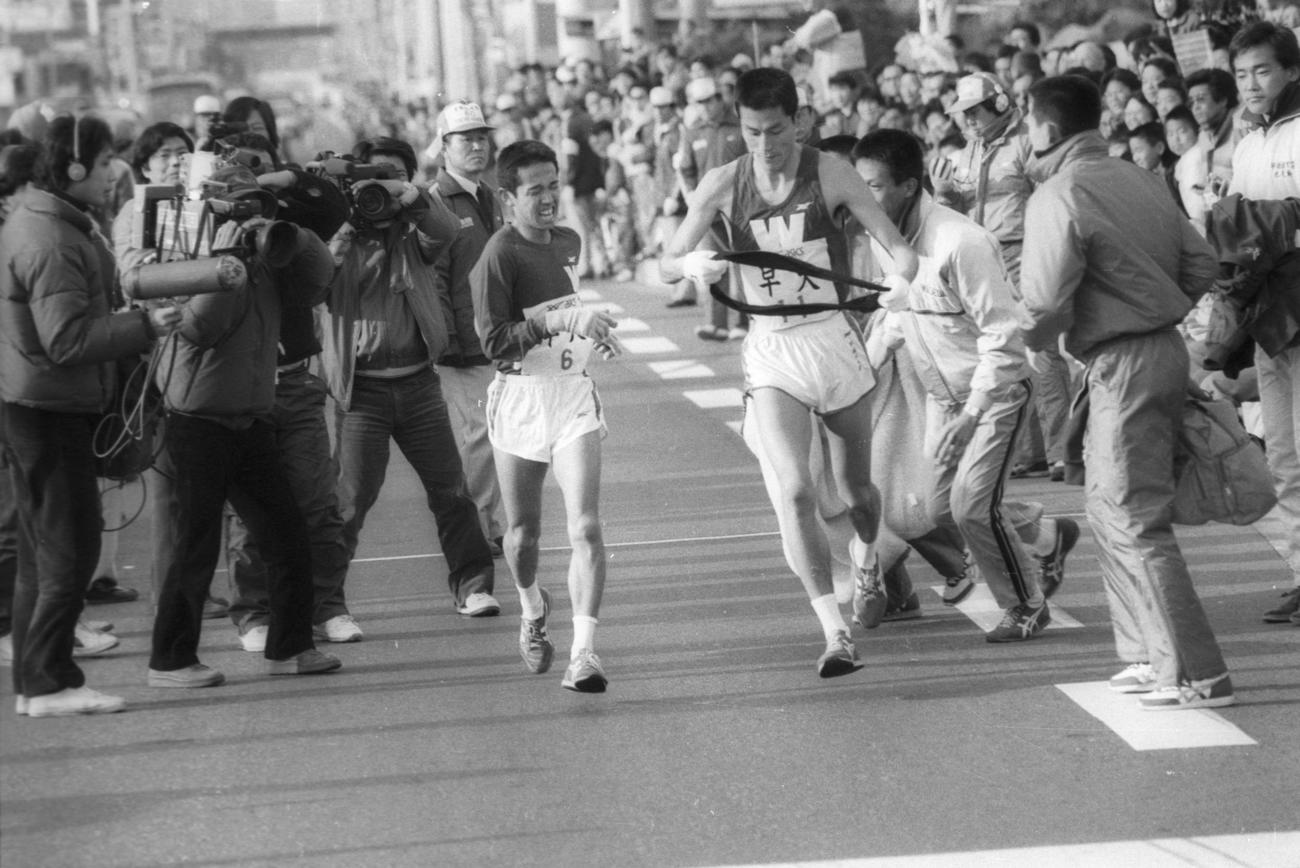 復路7区小田原中継所　2位との差を6分40秒に広げ7区伊藤雅弘（右＝4年、区間1位）にタスキリレーする早大・越智房樹（左＝3年、区間5位）＝1984年1月3日