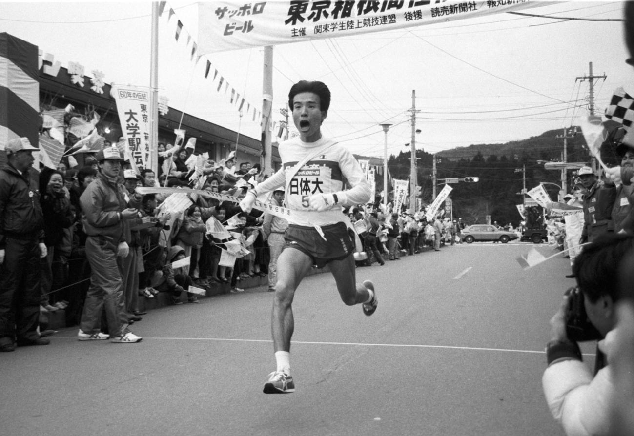 往路5区芦ノ湖駐車場　主将が欠場するアクシデントにめげず往路優勝のゴールテープを切る日体大・平山征志（3年、区間1位）＝1987年1月2日