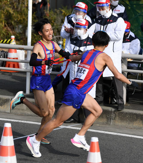 平塚中継所、トップでタスキをつなぐ創価大7区原富（左）と8区永井（撮影・横山健太）